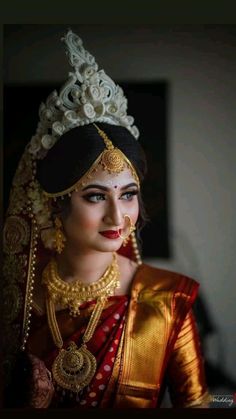 a woman wearing a red and gold sari with an elaborate head piece on her head