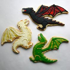 four decorated cookies with different designs and colors sitting on a white surface, one is green, the other is red