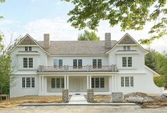 a large white house sitting in the middle of a forest