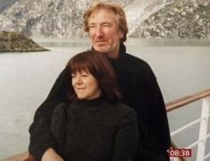 a man and woman are standing on the deck of a boat looking at the camera