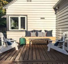 a wooden bench sitting on top of a wooden deck next to a white chair and table