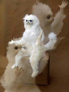 three white stuffed animals sitting on top of a wooden box with their arms in the air