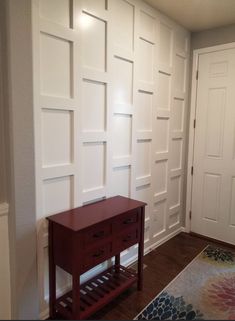 an empty room with white paneling on the walls and a red table next to it