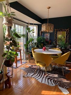 a dining room table surrounded by plants and chairs