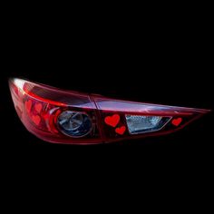 the tail light of a red car with hearts painted on it's side and black background