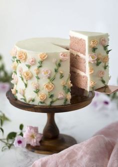 a cake with white frosting and pink flowers on the top is cut in half