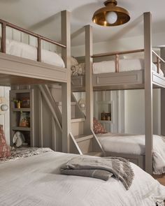 two bunk beds with white sheets and pillows