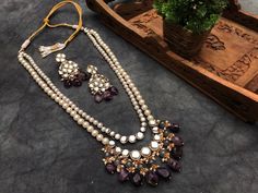 Amethyst and Kundan Long Layered Necklace Set For Women & Girls Material : Kundan, natural stone, faux pearl, glass, thread, and metal Dimension : Necklace - 28 x 2.5 inches approx. Earrings - 2.5 x 1 inches approx. Be the showstopper this wedding season with our Stone Kundan Long Layered Necklace Set. It has two layers of pearls and kundan stones. The second layer is given a royal look with grey colored glass beads and natural stones that dangle elegantly from kundan stones. Kundan stones, pear Elegant Purple Kundan Necklace For Festive Occasions, Elegant Purple Kundan Necklace For Wedding, Elegant Purple Kundan Necklace As Gift, Elegant Purple Jewelry Set For Festive Occasion, Long Kundan Necklace, Pakistani Necklace, Lavender Jewelry, Jewelry Indian Wedding, Lavender Jewellery