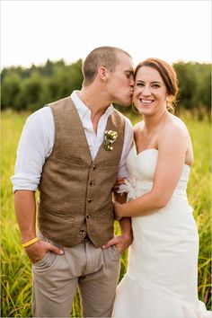 a man and woman standing next to each other in front of a grass covered field