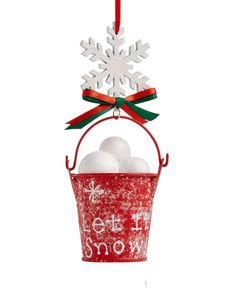 an ornament hanging from a red bucket filled with white balls and snowflakes