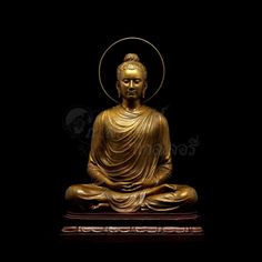 a golden buddha statue sitting on top of a wooden stand in front of a black background