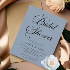 an elegant bridal shower is displayed on a table with flowers and gold ribbon around it