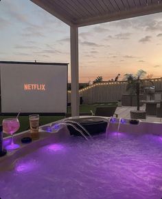 a hot tub with purple lights on the side and a movie screen in the back