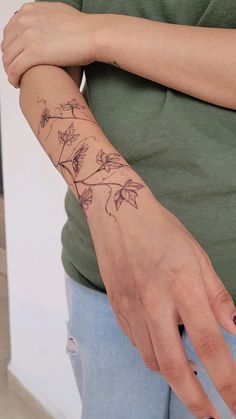 a woman's arm with flowers on it and her hand holding the wrist tattoo