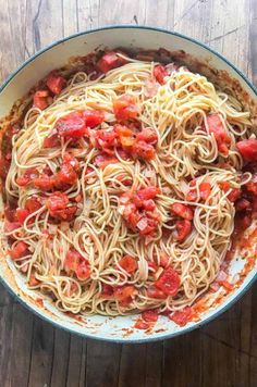 pasta with tomatoes and sauce in a pan on a wooden table, ready to be eaten