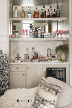 a living room filled with furniture and lots of bottles on top of the shelves next to a christmas tree