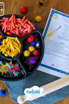 a black tray filled with lots of different colored food items next to a piece of paper