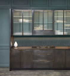 a kitchen area with cabinets, stove and vases on the counter top in front of it