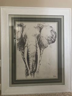 an elephant framed in a white frame on the floor next to a brown and black wall