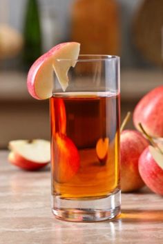 an apple slice is sticking out of the top of a glass filled with tea and apples