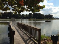 a boat traveling down a river next to a wooden pier