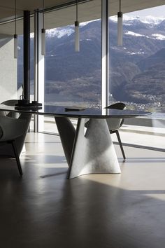 a dining room table with two chairs and a large window overlooking the mountain range in the background