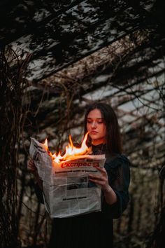 a woman holding a newspaper with flames coming out of it