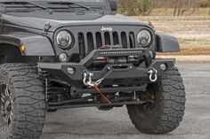 the front end of a black jeep with its lights on and an orange cord attached to it