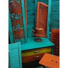 an old dresser and chair are painted teal green with orange accents on the top