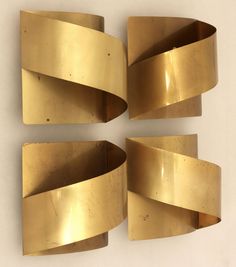 four pieces of art that are made out of gold colored metal and have curved ends