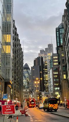 the city street is lined with tall buildings and construction signs in front of traffic cones