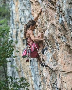 a woman climbing up the side of a mountain