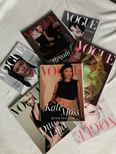 four magazines laying on top of each other next to a white bed sheet with the covers pulled down