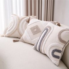 two pillows sitting on top of a white couch