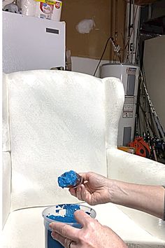 a woman is painting a white chair with blue paint