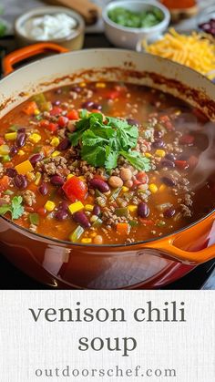 a red pot filled with chili soup next to bowls of cheese and other food items