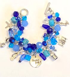 Beach themed charm bracelet perfect for the beach loving girl. Bracelet features blue and aqua toned beads and is made up of different silver tone beach themed charms such as: a starfish, sunglasses, flip flop, umbrella with lounge chairs, bucket and shovel, and a mermaid. Bracelet is approximately 7.5 inches. I am happy to resize bracelet at no additional charge. Blue Bracelets With Lobster Clasp For Beach, Handmade Blue Charm Bracelet For Beach, Blue Beaded Strand Bracelet With Starfish Charm, Ocean-inspired Blue Charm Bracelet For Gifts, Fun Beach Season Jewelry For Vacation, Blue Beaded Jewelry For Beach Party, Casual Blue Jewelry With Starfish Charm, Fun Blue Jewelry For Summer, Blue Beachy Jewelry For Vacation