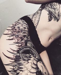 a woman laying on the ground with her stomach covered in black and white tattoo designs