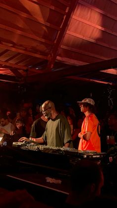 two men in orange shirts are djing at a party