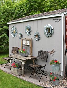 a small shed with flowers on the wall and chairs around it, along with other outdoor furniture