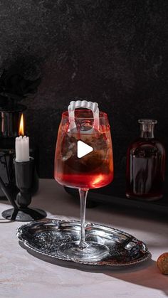 a glass filled with liquid sitting on top of a metal tray next to bottles and candles