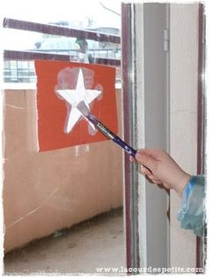 a person holding a paintbrush in front of a red and white star cutout