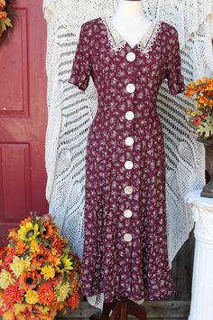 Beautiful floral acetate/rayon dress bestowing white flowers on a burgundy background make this dress a perfect tea party, garden party dress, for office, secretary, academia, church wear, etc.! Dress bestows a v-neckline with lacey off white collar, padded shoulders, short sleeves, large pearly front button closure, has a lace up back for a more fitted waist style that flares out around hips and is around calf length depending on your height. Dress is in excellent vintage condition showing minimal wear for its age. Please seem all photos as this is part of description. Tag states this as being a size 11 / 1 2, but this is vintage sizing so please check all measurements for best fit. Pictures were taken using a size 8 dress form and it fit this size quite nicely. Measurements are taken wit Ladies Tea Party, Dress For Office, Office Academia, Ladies Tea, Victorian Fashion Dresses, Tee Party, Dress Office, 90s Floral, Ladies Wear