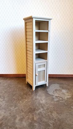 a small wooden cabinet with one door open on the floor next to a wallpapered wall