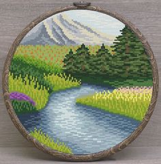 a cross stitch picture of a mountain stream