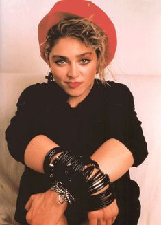 a woman in black shirt and red hat with her arms crossed