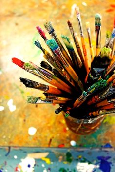 a cup filled with lots of different types of paintbrushes on top of a table