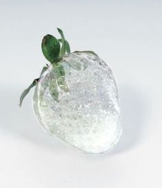 a small green frog sitting on top of a white object with water droplets all over it