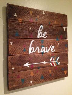 a wooden sign that says be brave with an arrow and arrows painted on the side