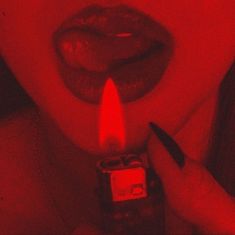 a woman holding a lighter in front of her face with red light coming from it